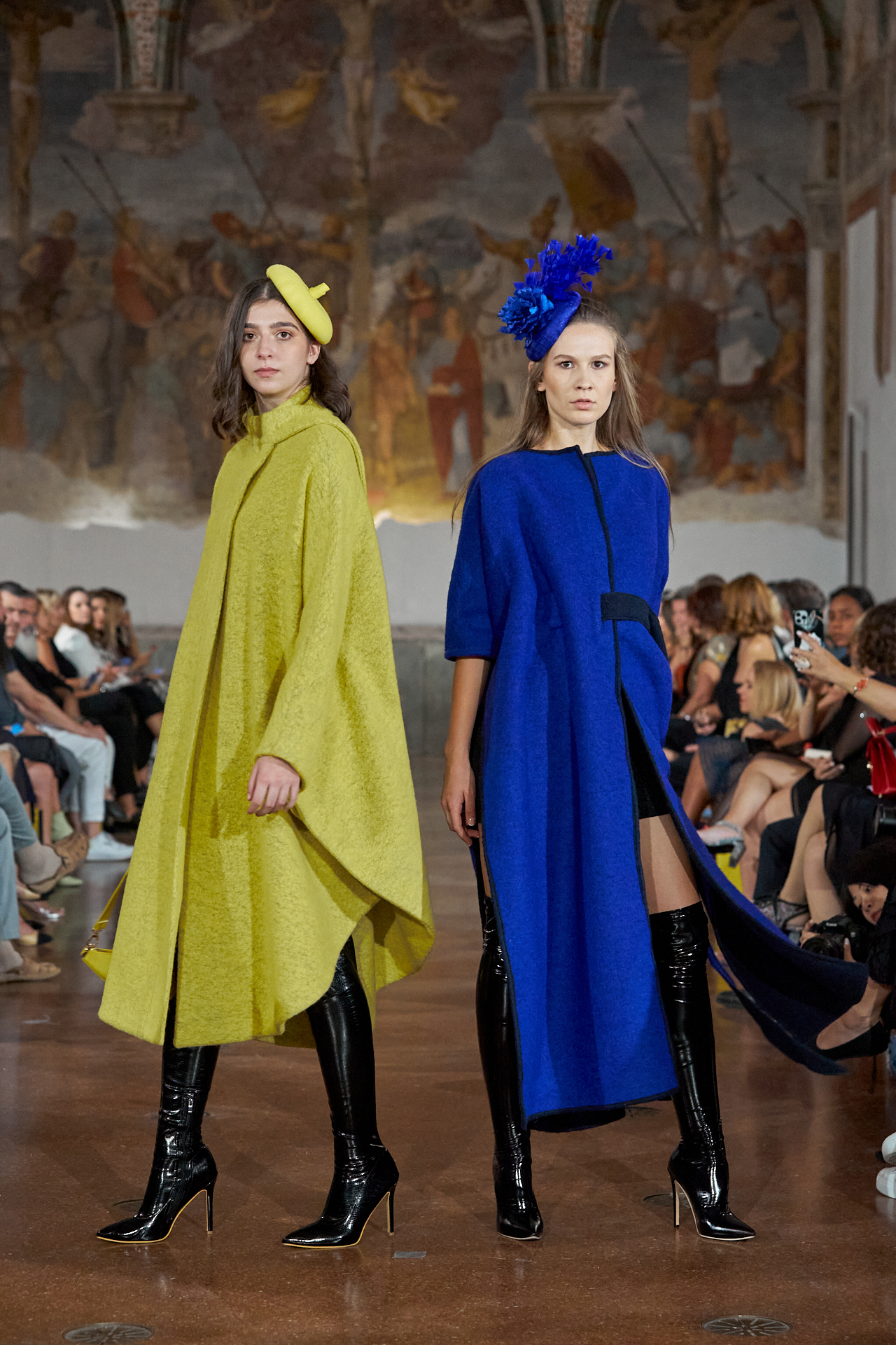 Runway look: model in yellow beret-style cape alongside model in cobalt blue coat