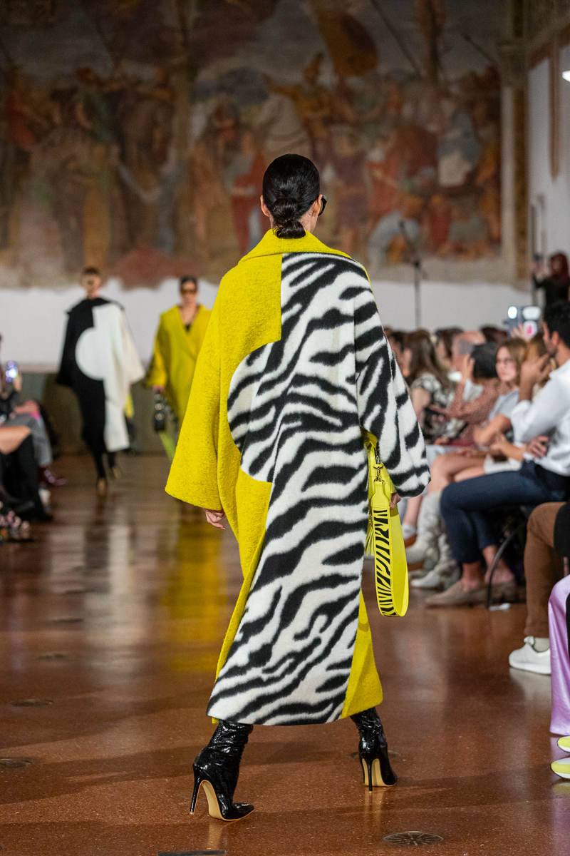 Runway look: model from behind wearing yellow and black-and-white zebra-print coat